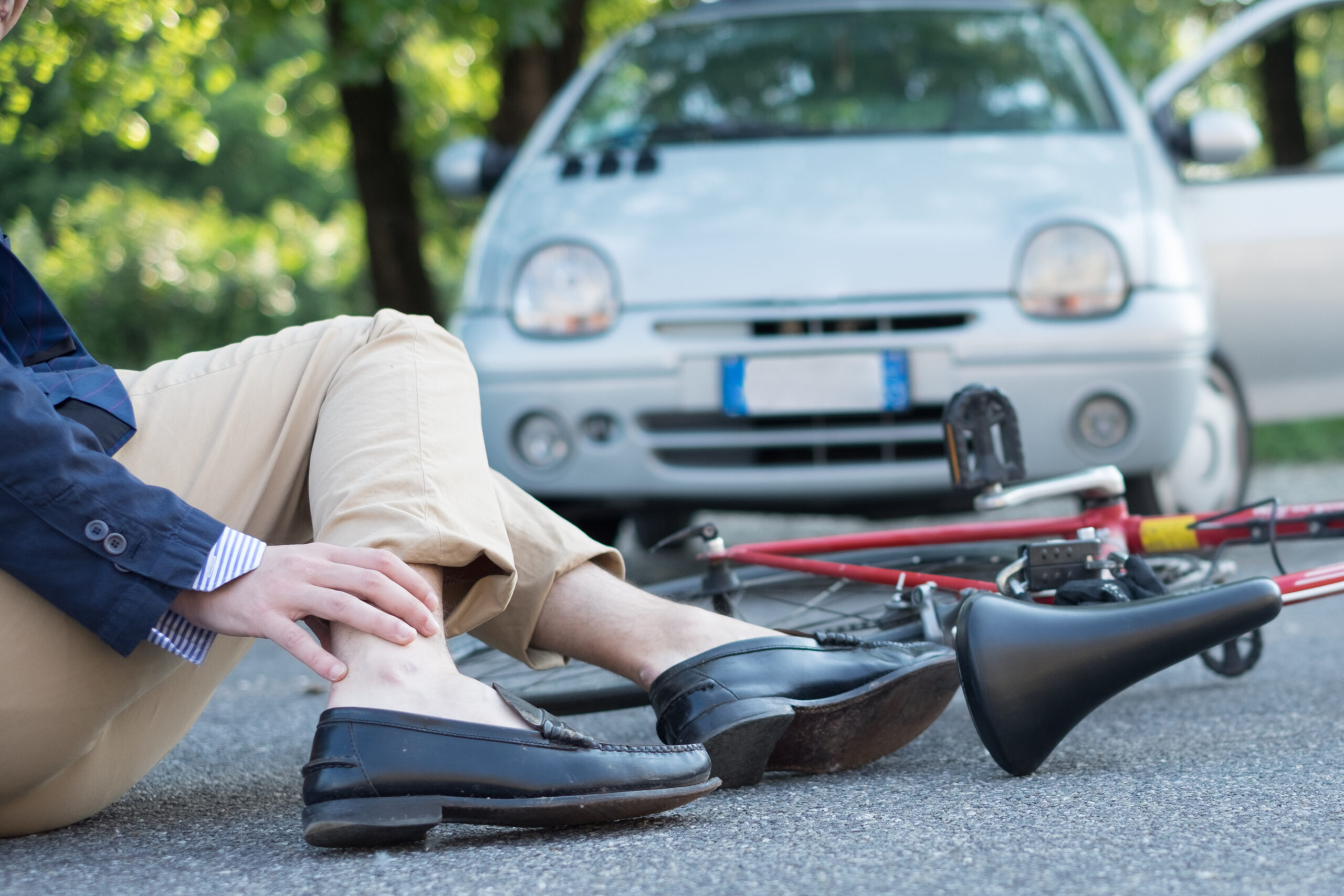 Cyclist holding ankle after bicycle accident